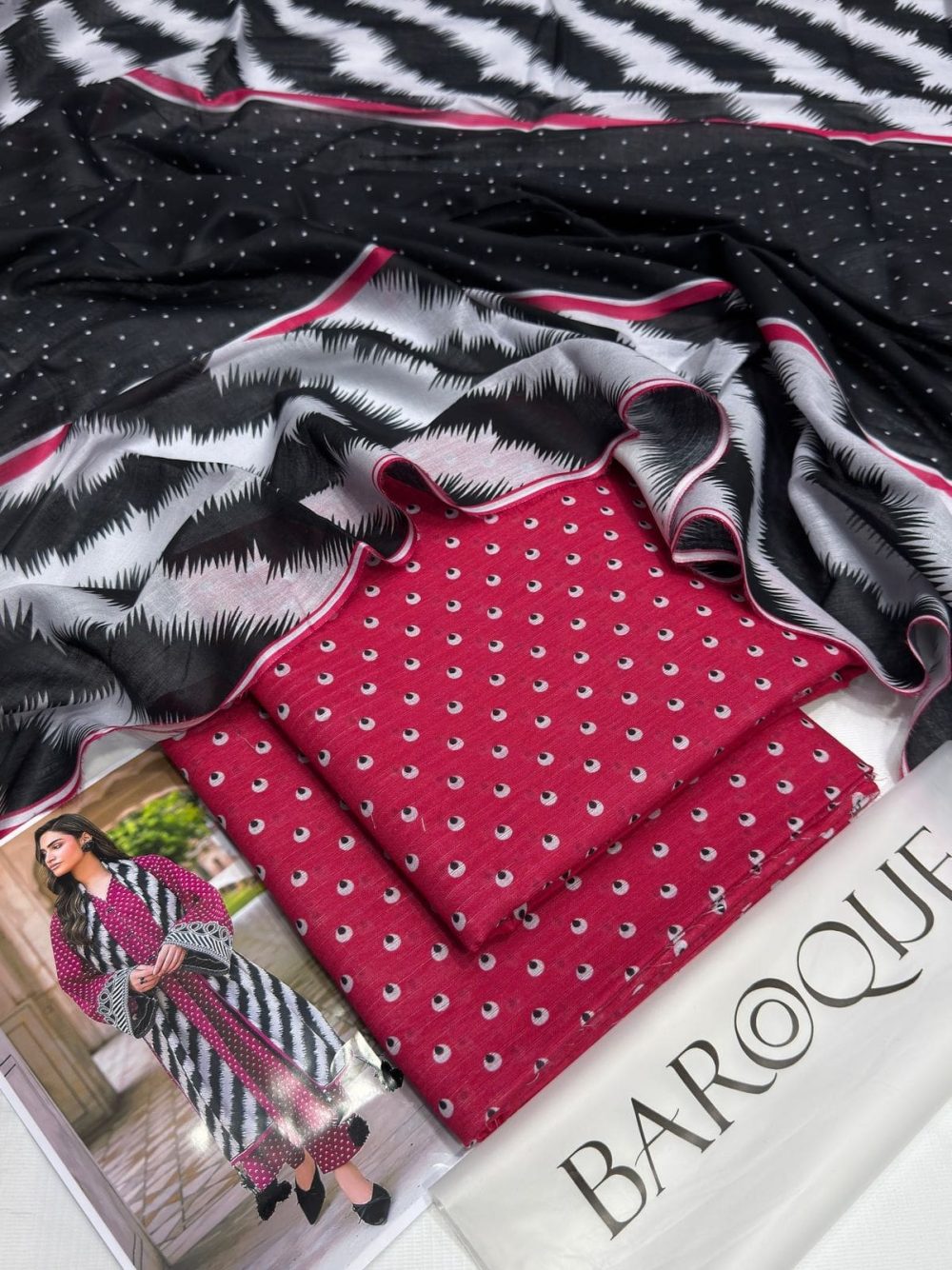 Flatlay of Baroque pink lawn suit with printed dupatta and folded shirt fabric